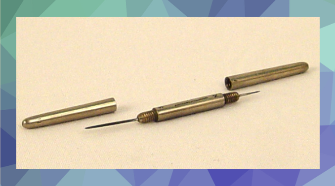 Grey metal cylindrical object with a needle coming out both sides and two caps sitting beside it.